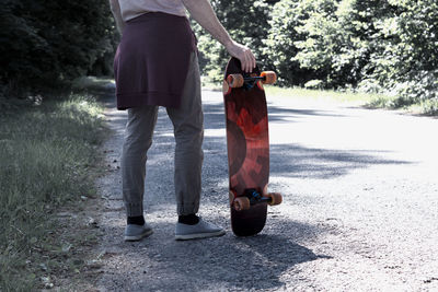 Low section of man with skateboard standing on footpath