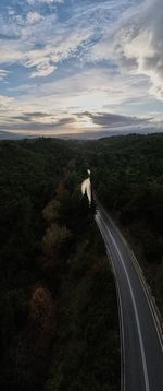 Road amidst trees against sky during sunset