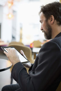 Side view of businessman using digital tablet in hotel restaurant