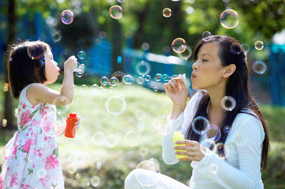 Mother and daughter blowing bubbles at park