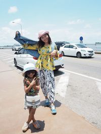 Portrait of happy young woman on road against sky