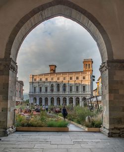 Buildings against sky seen through arch window