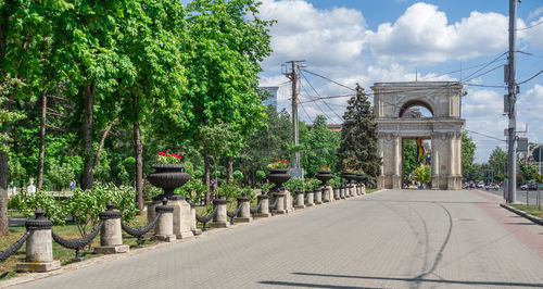 Footpath amidst trees and bridge against sky