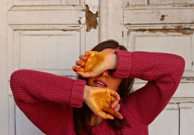 Woman covering face while standing against door