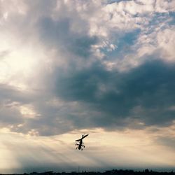 Low angle view of airplane flying against cloudy sky