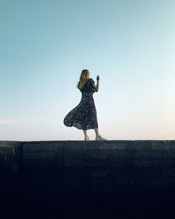 Rear view of woman standing against clear sky