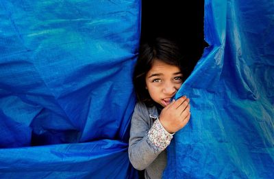 Close-up portrait of child hiding behind tarpaulin