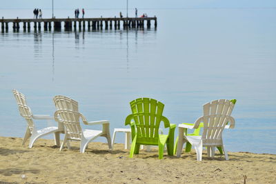 Empty chairs on beach against sky