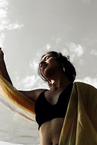 Low angle view of woman looking away against sky