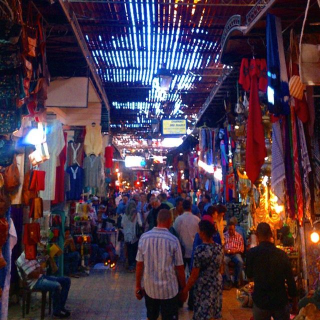 illuminated, large group of people, men, market, person, night, market stall, lifestyles, retail, lighting equipment, street, built structure, crowd, leisure activity, architecture, city life, shopping, walking, building exterior