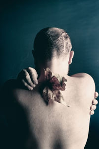 Rear view of shirtless man against wall