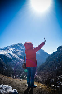 Rear view of man standing on mountain against sky. 