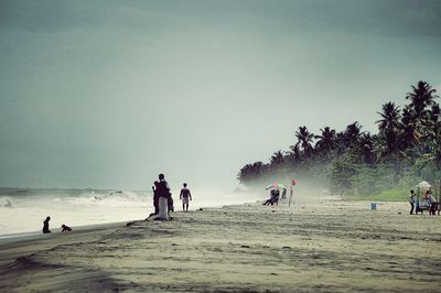 People on beach against clear sky