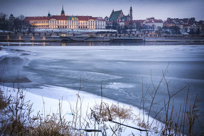 View of buildings by river during winter