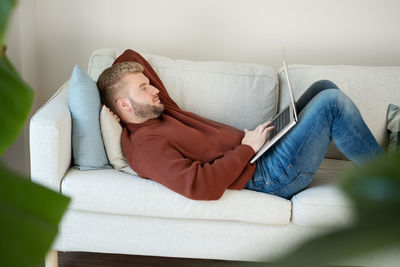 Low section of woman sitting on sofa at home