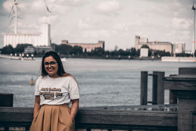 Portrait of smiling woman sitting against sky