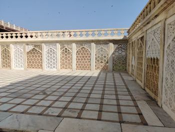 Footpath amidst buildings against clear blue sky