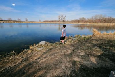 Rear view of boy in lake against sky