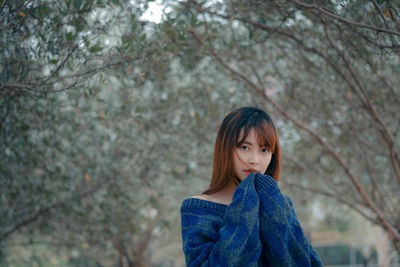 Portrait of woman standing against tree during winter