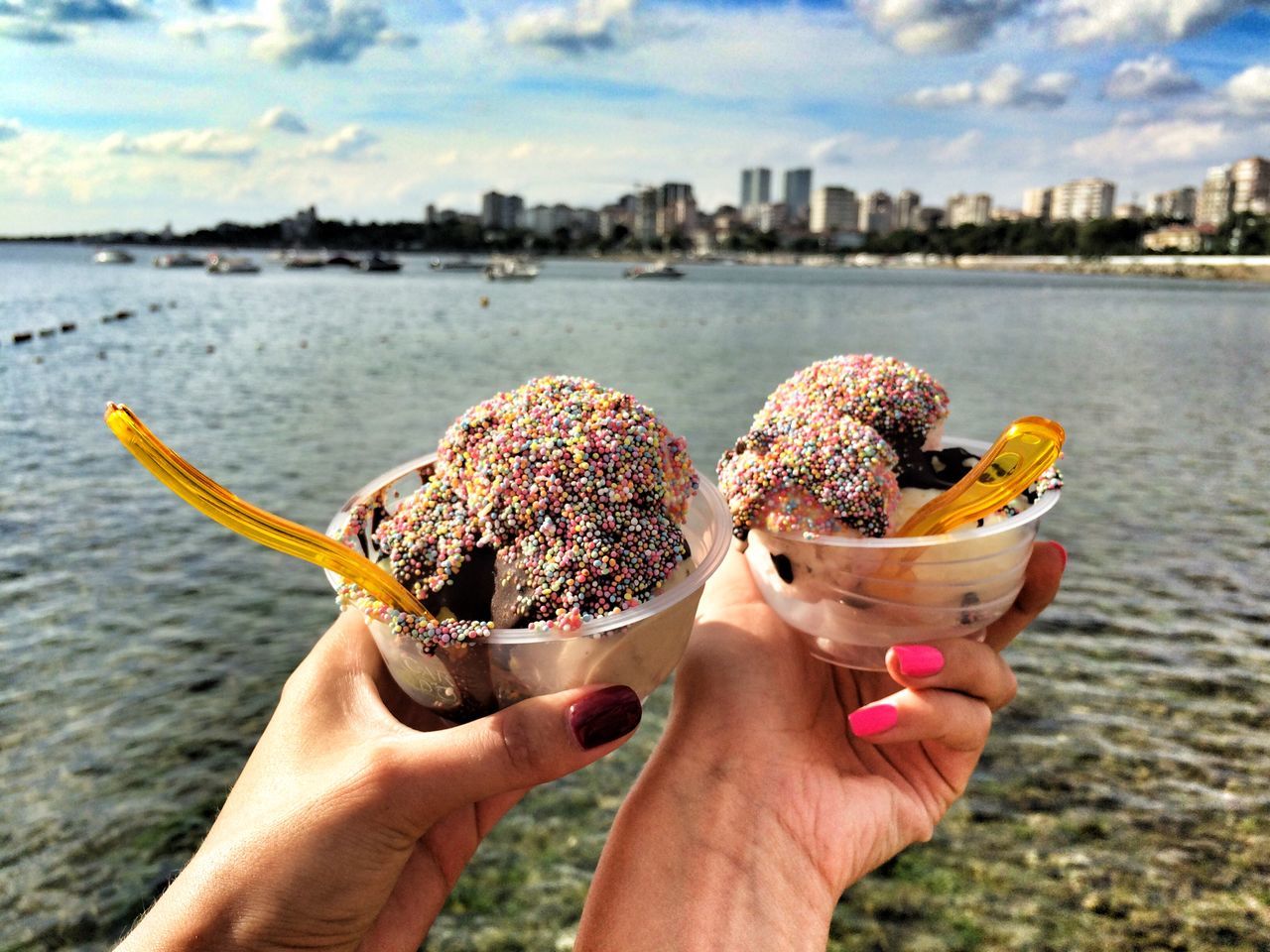 person, holding, personal perspective, part of, unrecognizable person, cropped, lifestyles, food and drink, leisure activity, human finger, water, focus on foreground, food, sky, freshness, sweet food, indulgence