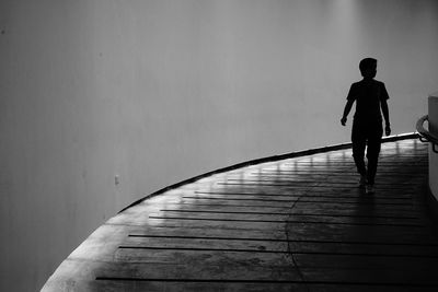 Rear view of silhouette man walking on footpath