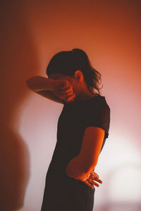 Side view of sad woman standing by wall at home