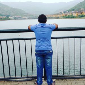 Rear view of man standing by railing against mountain