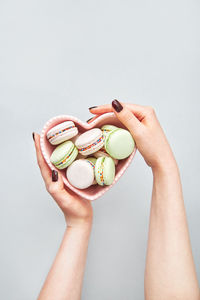 Woman holding heart shaped bowl of macarons. top view