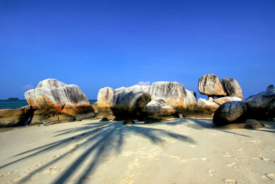 Rocks on beach against clear blue sky