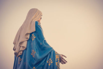 Low angle view of women standing against blue sky