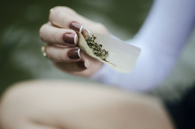 Midsection of woman holding marijuana joint