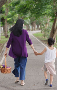 Rear view of women with daughter walking on road