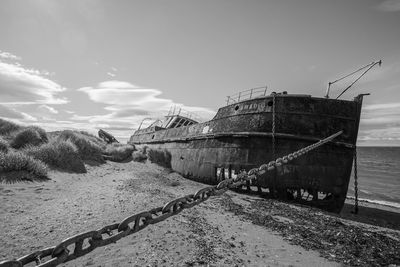 View of abandoned ship in sea against sky