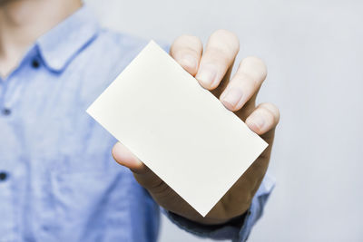 Close-up of hand holding paper against white background
