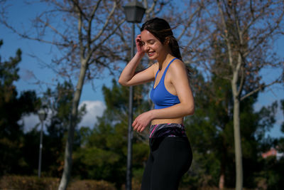 Smiling young woman standing against trees