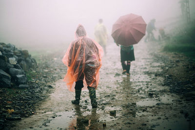 Rear view of people walking in rain