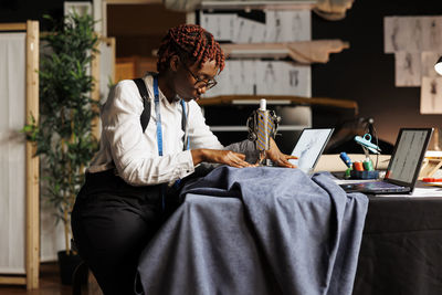 Young woman using laptop while sitting on sofa at home