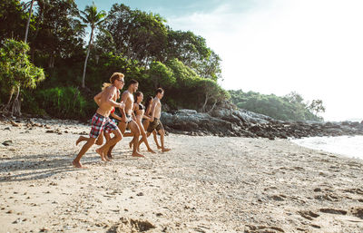 Full length of friends enjoying at beach against sky