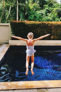 Full length rear view of girl jumping in swimming pool