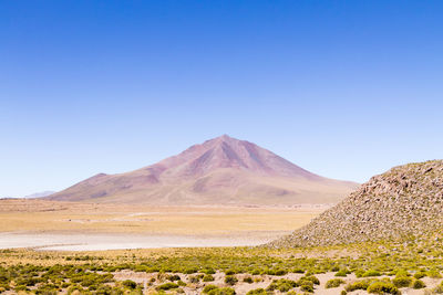 Scenic view of arid landscape against clear blue sky