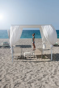 Woman looks at beach with loungers in greece towards the horizon