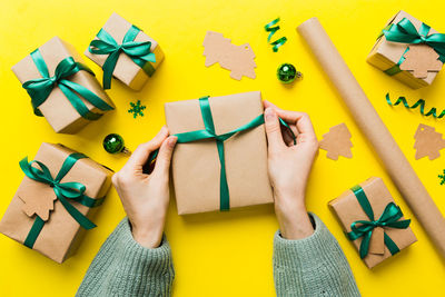 Cropped hand of woman holding christmas presents on table