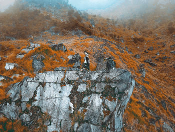 The view of a large rock on top of which there are 2 climbers  