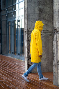 Side view of man wearing raincoat walking on footpath