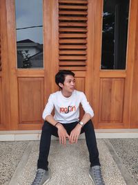 Portrait of young man sitting at entrance of building