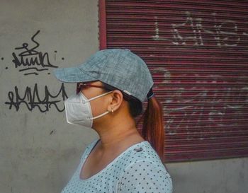 Midsection of woman wearing sunglasses standing against wall