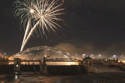 Firework display over river against sky at night