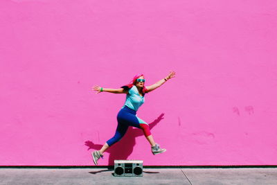 Low angle view of woman climbing on pink wall