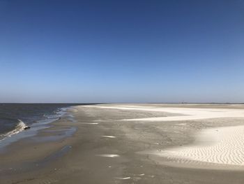 Scenic view of beach against clear blue sky