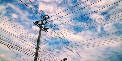 Low angle view of power lines against cloudy sky